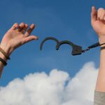 Symbolic image of freedom with open handcuffs against a bright blue sky.