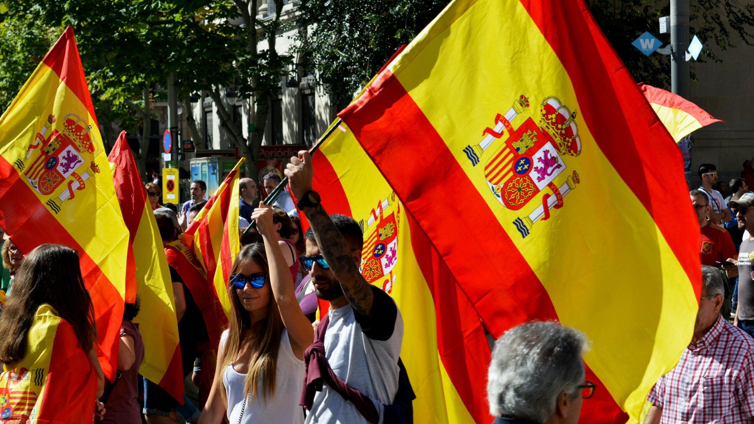 Vibrant street rally in Barcelona with people waving Spanish flags, capturing a lively outdoor atmosphere.